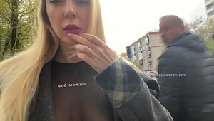 A girl shows her breasts while walking in public in the city