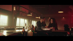 man and woman smooching sitting in bar with pink lights